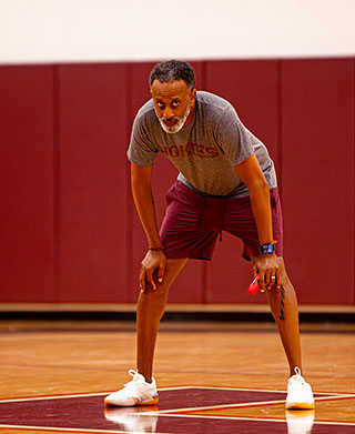 Coach Kenny Brooks on the basketball court, looking after his players.