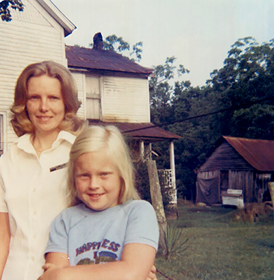 Park Ranger Saundra Tomlinson in 1974 standing with a child in front of a home