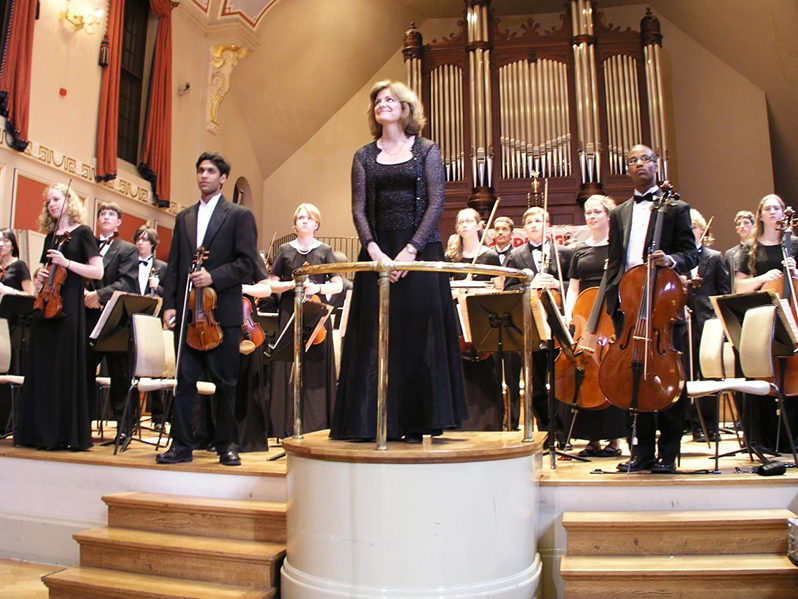 Laura Thomas and the orchestra stand for applause at the end of their performance.