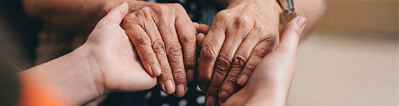Decorative. A pair of older hands holding onto a pair pf younger hands.