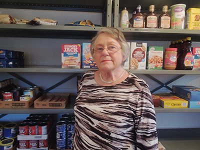photo of Anne Stiles standing in front of food pantry shelves