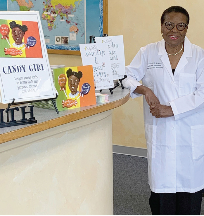 portrait of Elizabeth Green wearing a white lab coat leaning with her right elbow on a counter upon which several books are displayed